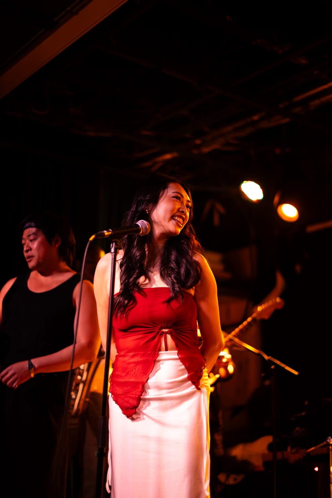 A Takes a Village vocalist smiles at the mic beside her bandmates at The Drake Underground in Toronto
