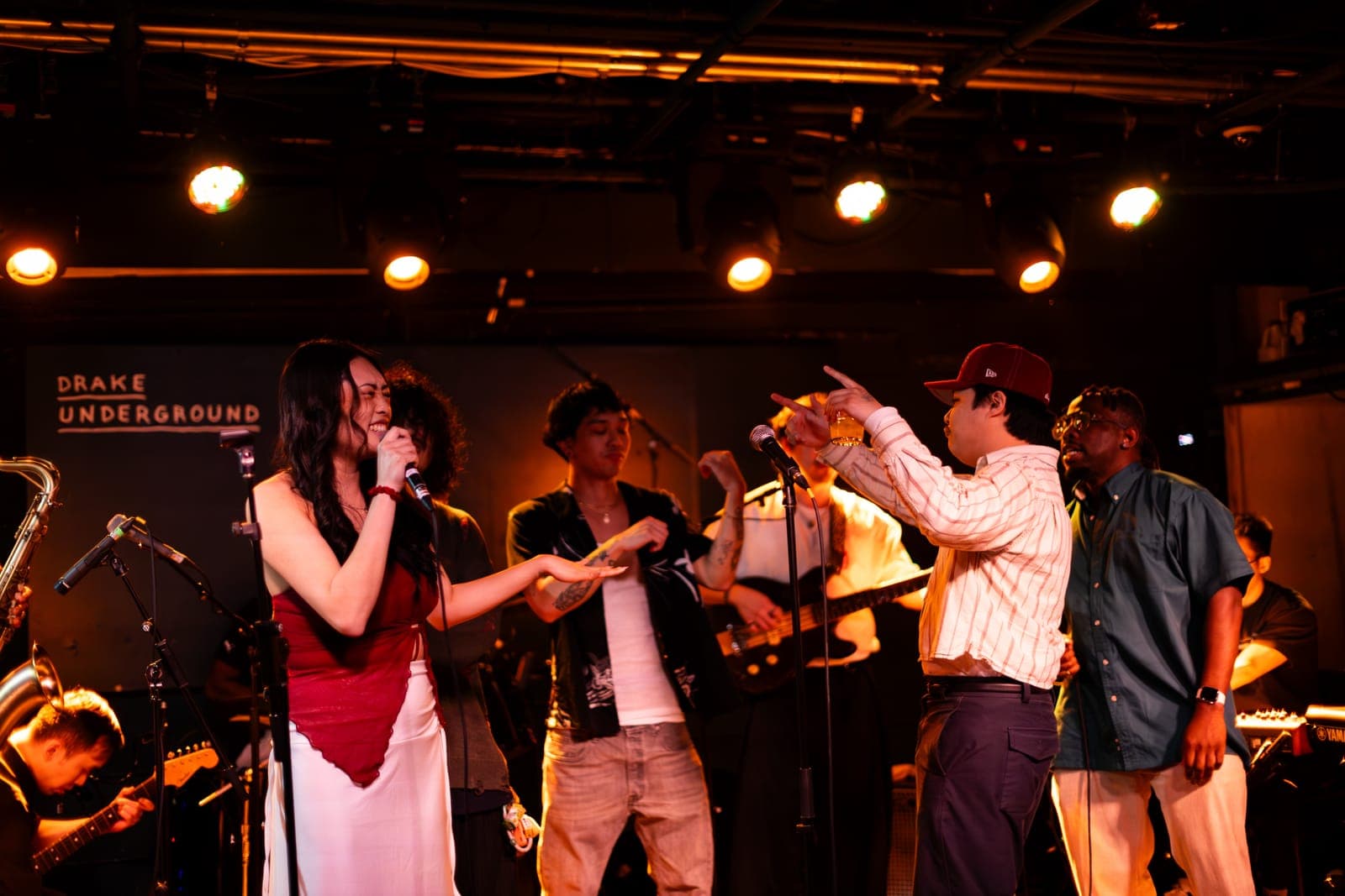 A Takes a Village vocalist trades lines with bandmates onstage at The Drake Underground in Toronto
