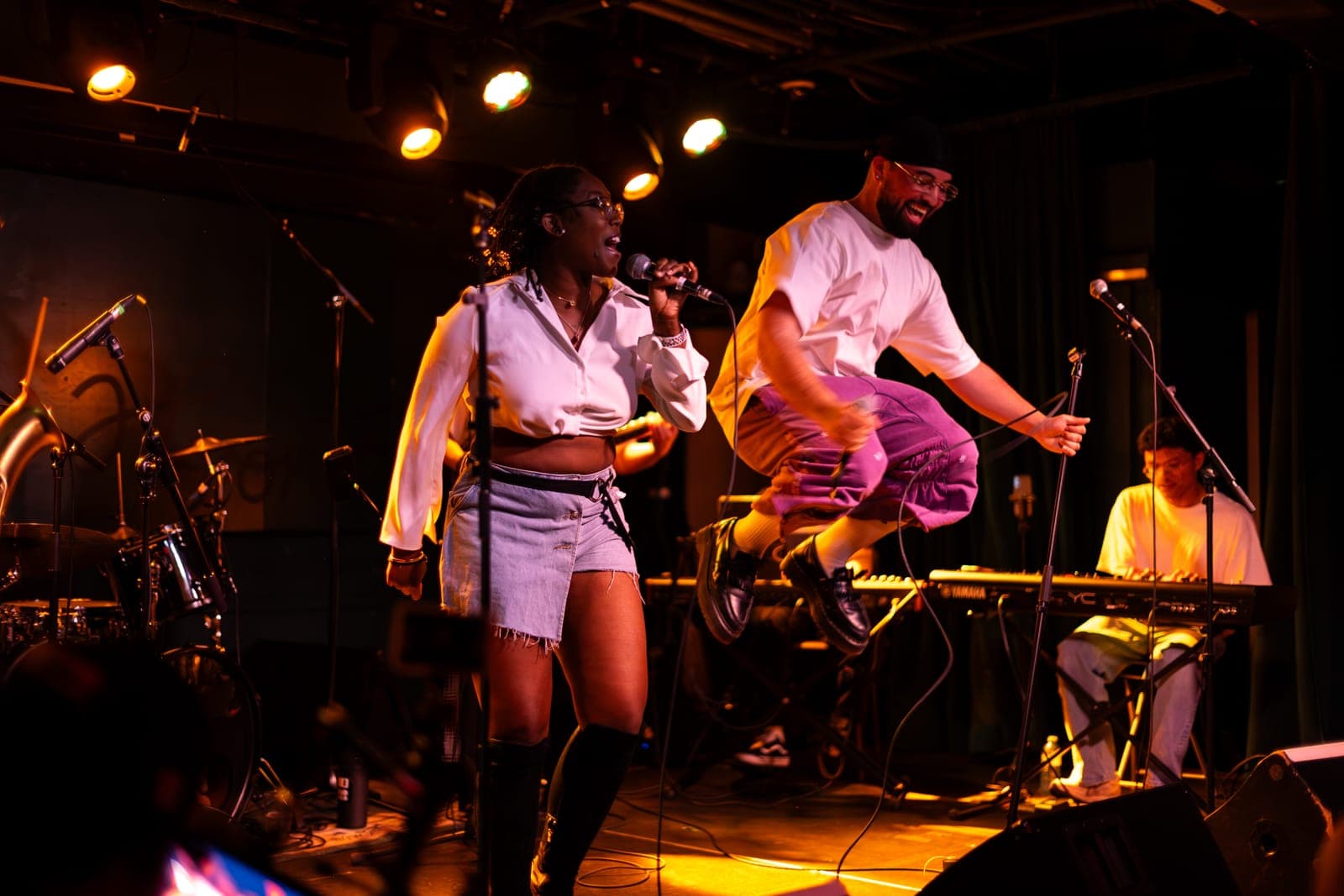 A Takes a Village singer performs as a bandmate leaps mid-air beside the keyboardist at The Drake Underground in Toronto