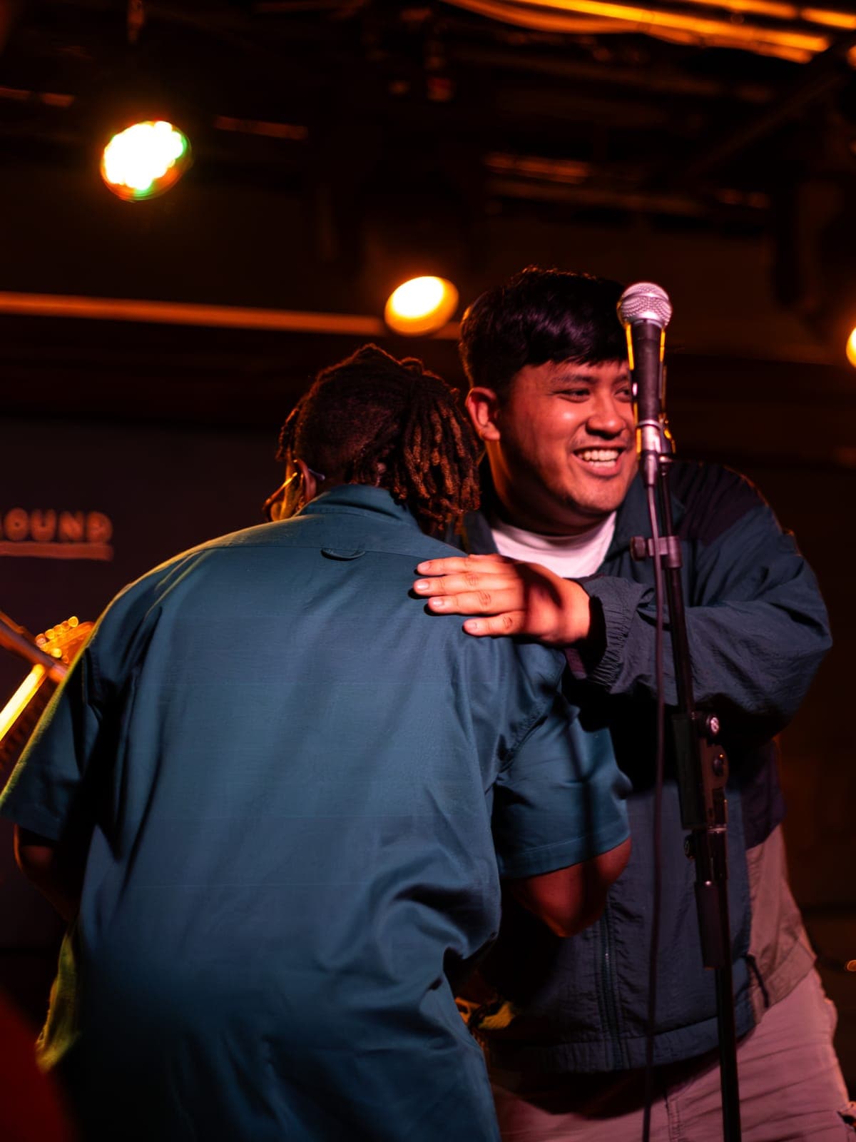 Two Takes a Village members share a hug at the mic mid-set at The Drake Underground in Toronto