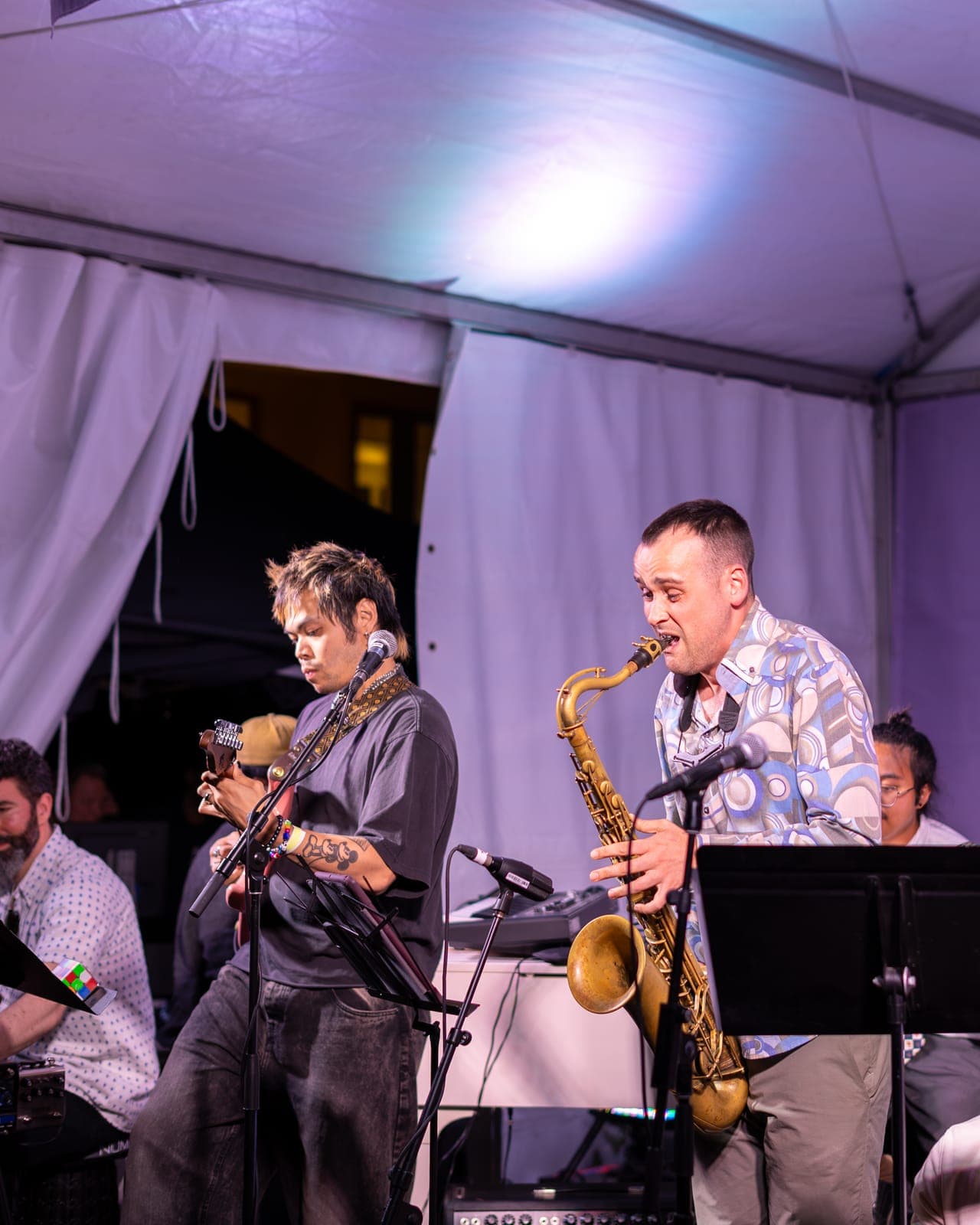 A saxophonist leans into his solo beside the guitarist-vocalist as Duck Society plays under the tent at the OLG Village stage
