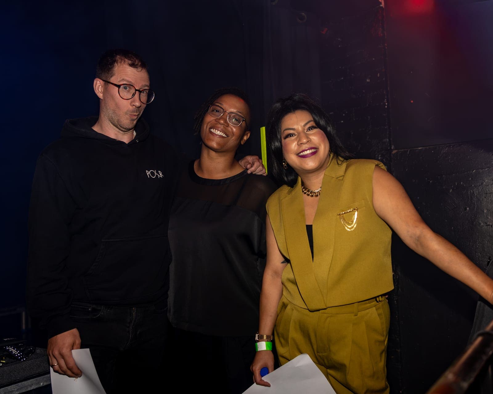 Maya Killtron and two bandmates pose together, smiling, backstage after the show