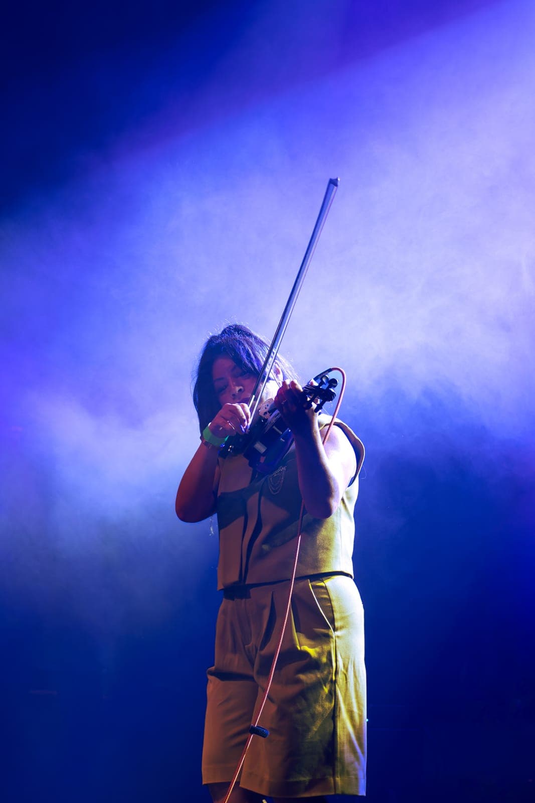 Maya Killtron draws her bow across an electric violin, wreathed in blue haze at Danforth Music Hall