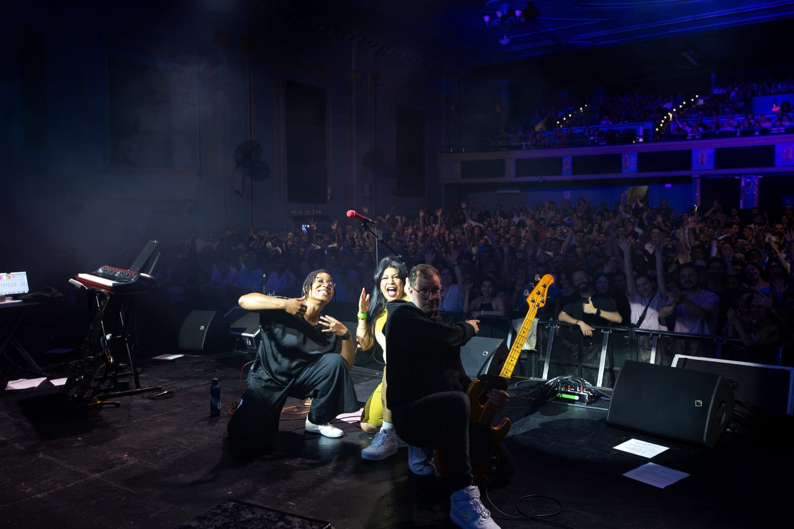 Maya Killtron and two bandmates kneel at the stage edge, beaming, with the full Danforth Music Hall crowd behind them