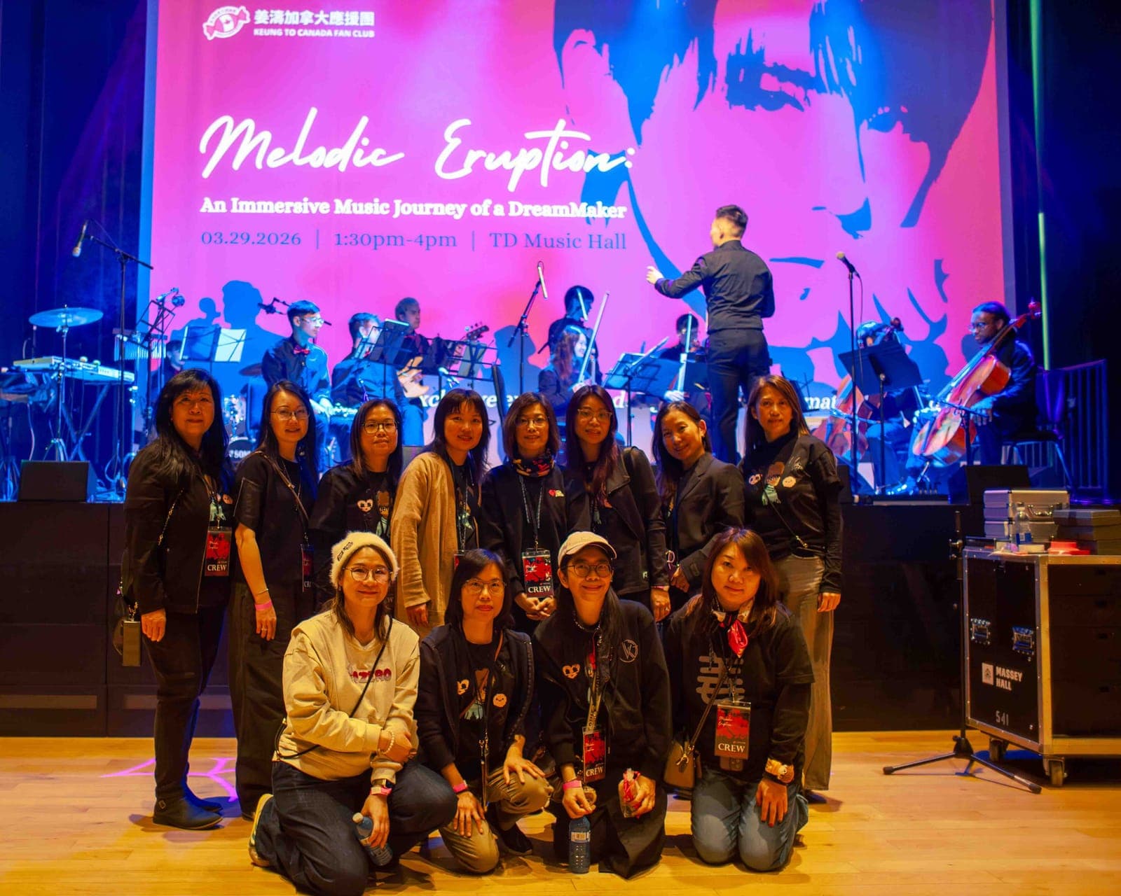 The Keung To Canada Fan Club team pose in front of the 'Melodic Eruption' stage screen at TD Music Hall in Toronto