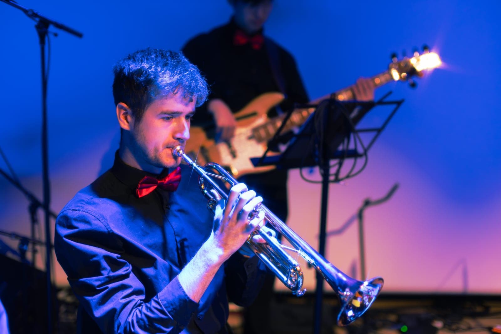 A trumpeter in a red bow tie plays with the Toronto Pops Orchestra under blue light at TD Music Hall in Toronto