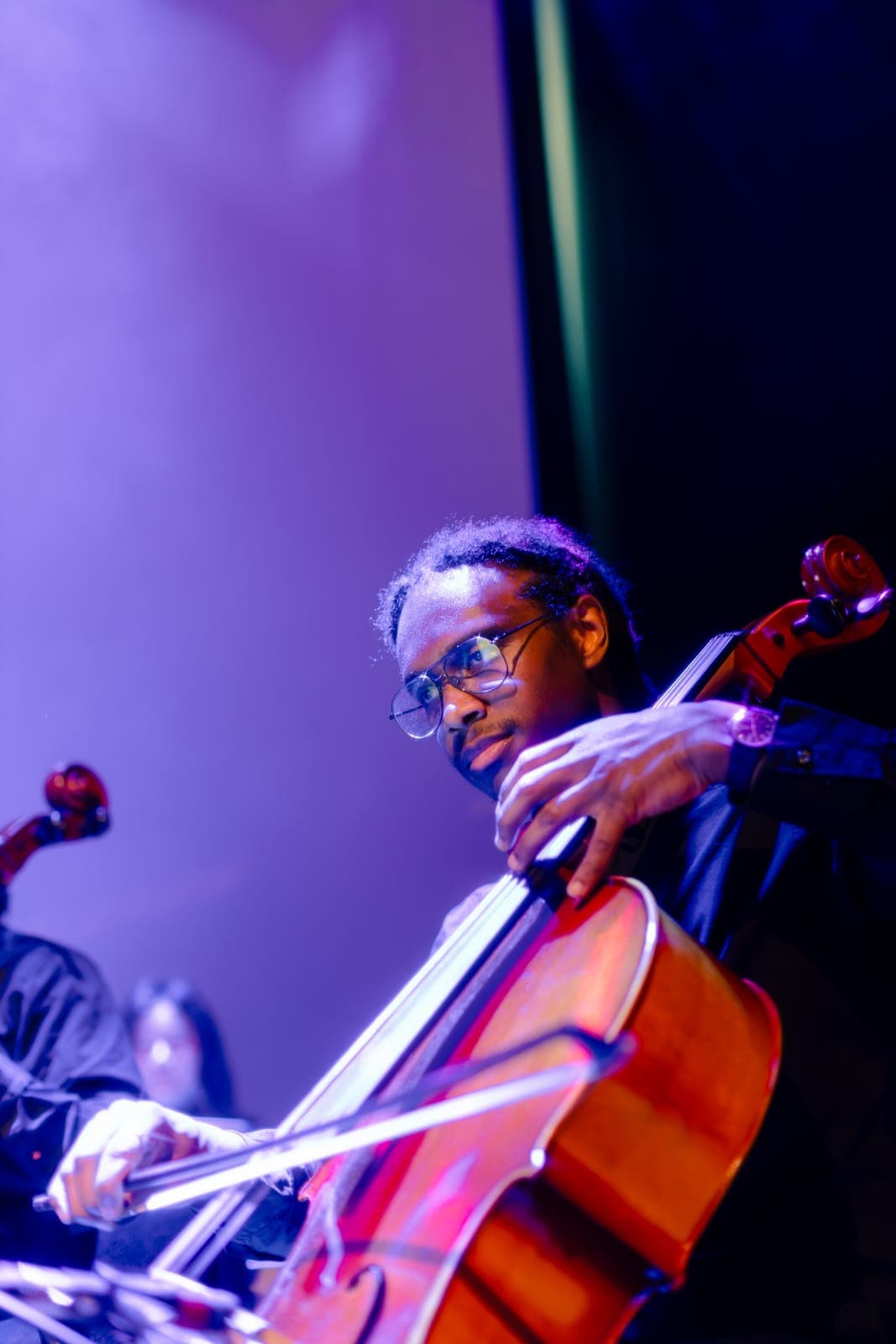 A cellist plays with the Toronto Pops Orchestra under purple light at the Keung To fan event at TD Music Hall in Toronto