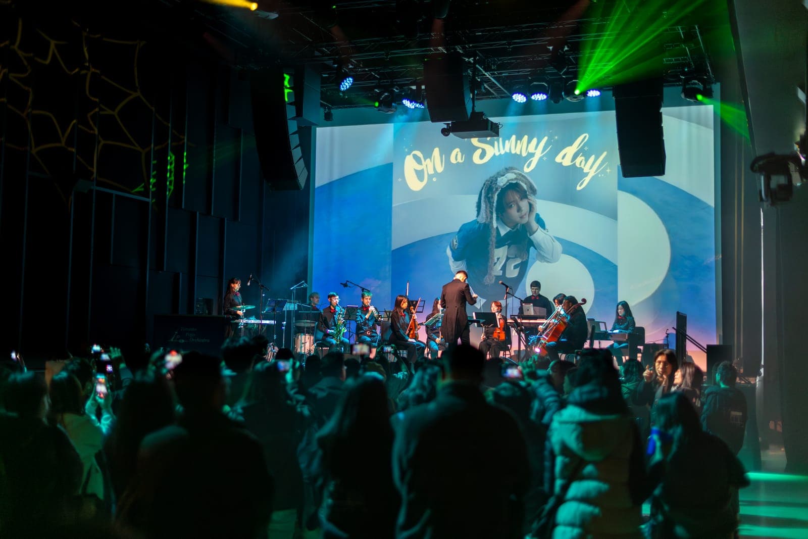 The Toronto Pops Orchestra performs beneath an 'On a Sunny Day' Keung To visual as fans film at TD Music Hall in Toronto