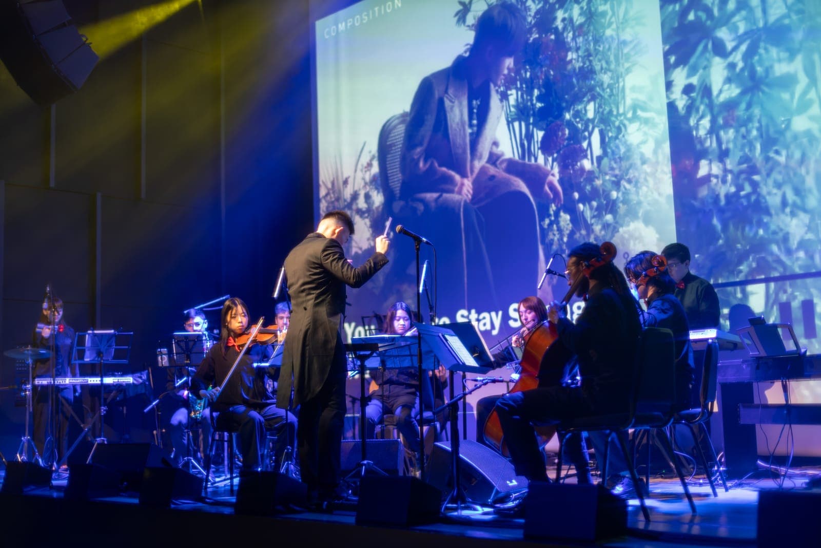 The Toronto Pops Orchestra performs under blue light as a Keung To visual fills the screen behind at TD Music Hall in Toronto