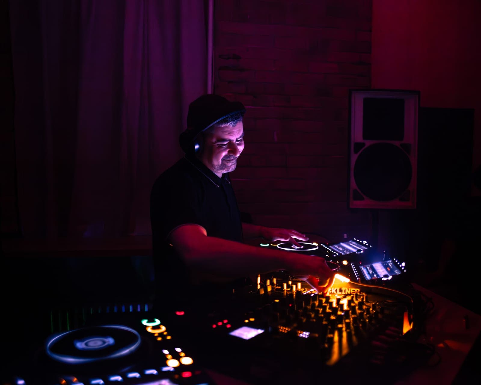 Al-P mixes intently in a cap and headphones under red light at Rhythm in Toronto
