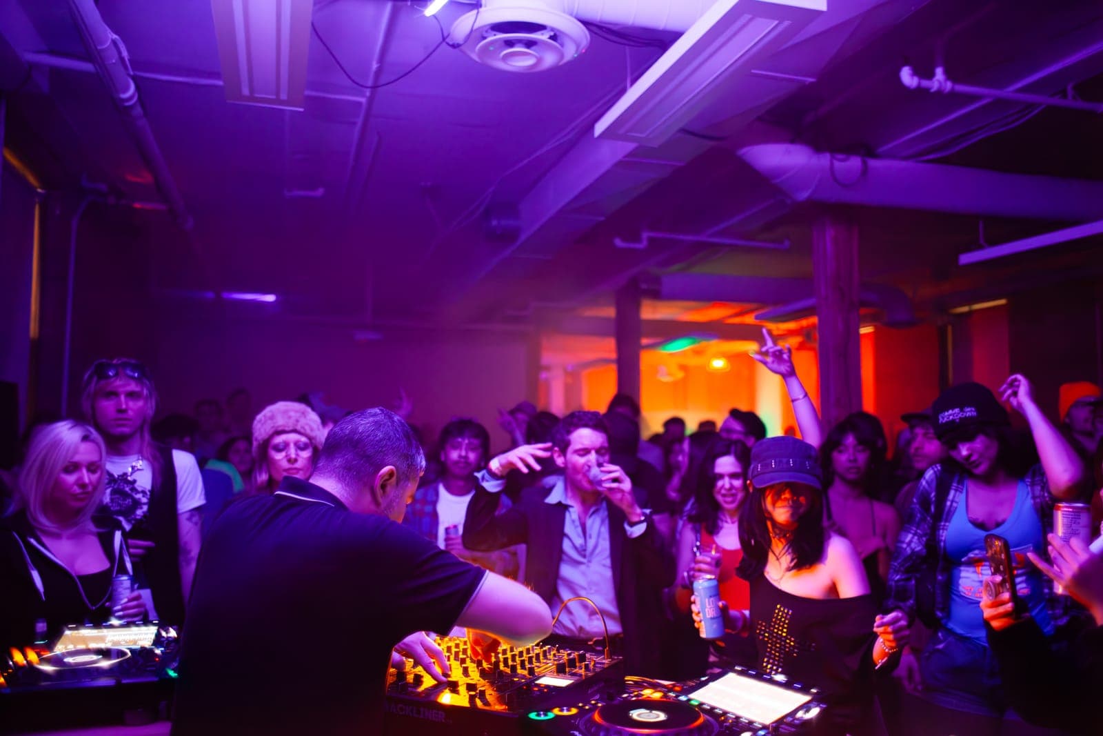Al-P plays to a dancing crowd, a warm glow at the back of the room, at Rhythm in Toronto