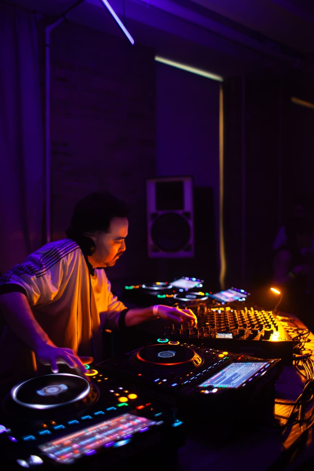 Kiinjo leans over the glowing CDJs in profile under purple light at Rhythm in Toronto
