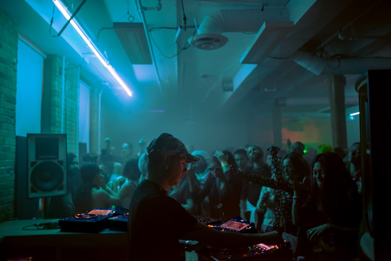 Tiga mixes in a camo cap before a foggy, teal-lit crowd at Rhythm in Toronto