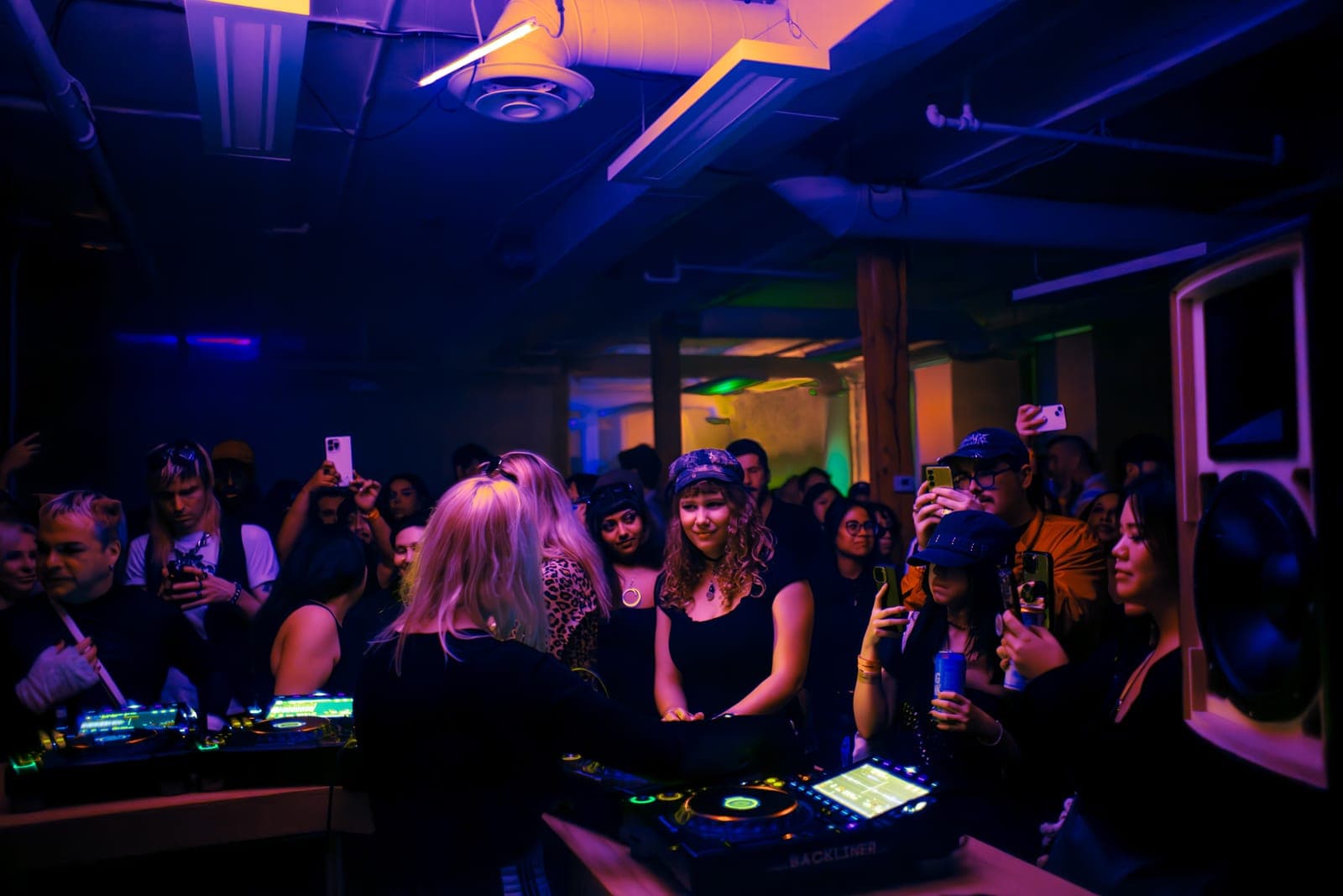 Uffie performs behind the CDJs as fans film on their phones in teal light at Rhythm in Toronto