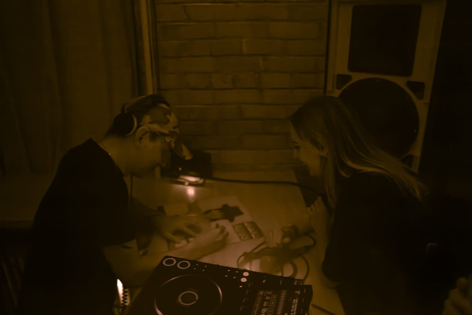 Warm-toned shot of Tiga in headphones mixing beside a dancer at Rhythm in Toronto