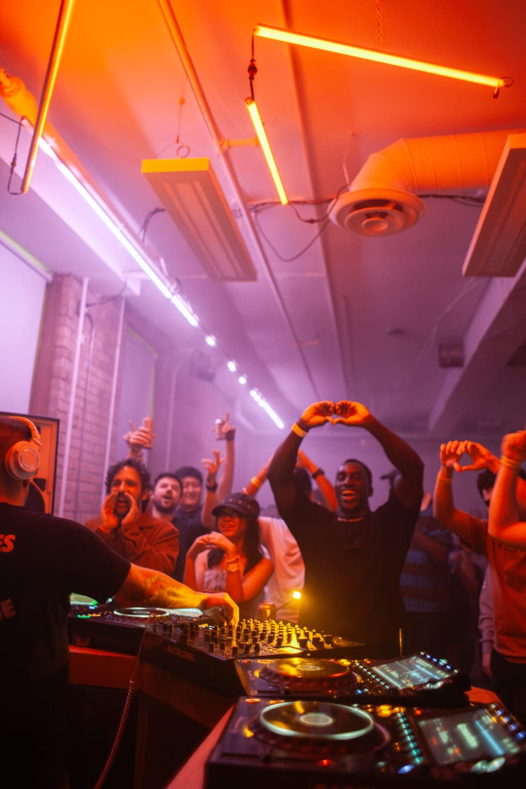 A fan forms a heart with his hands in the crowd as Todd Edwards reaches over the decks at Rhythm in Toronto