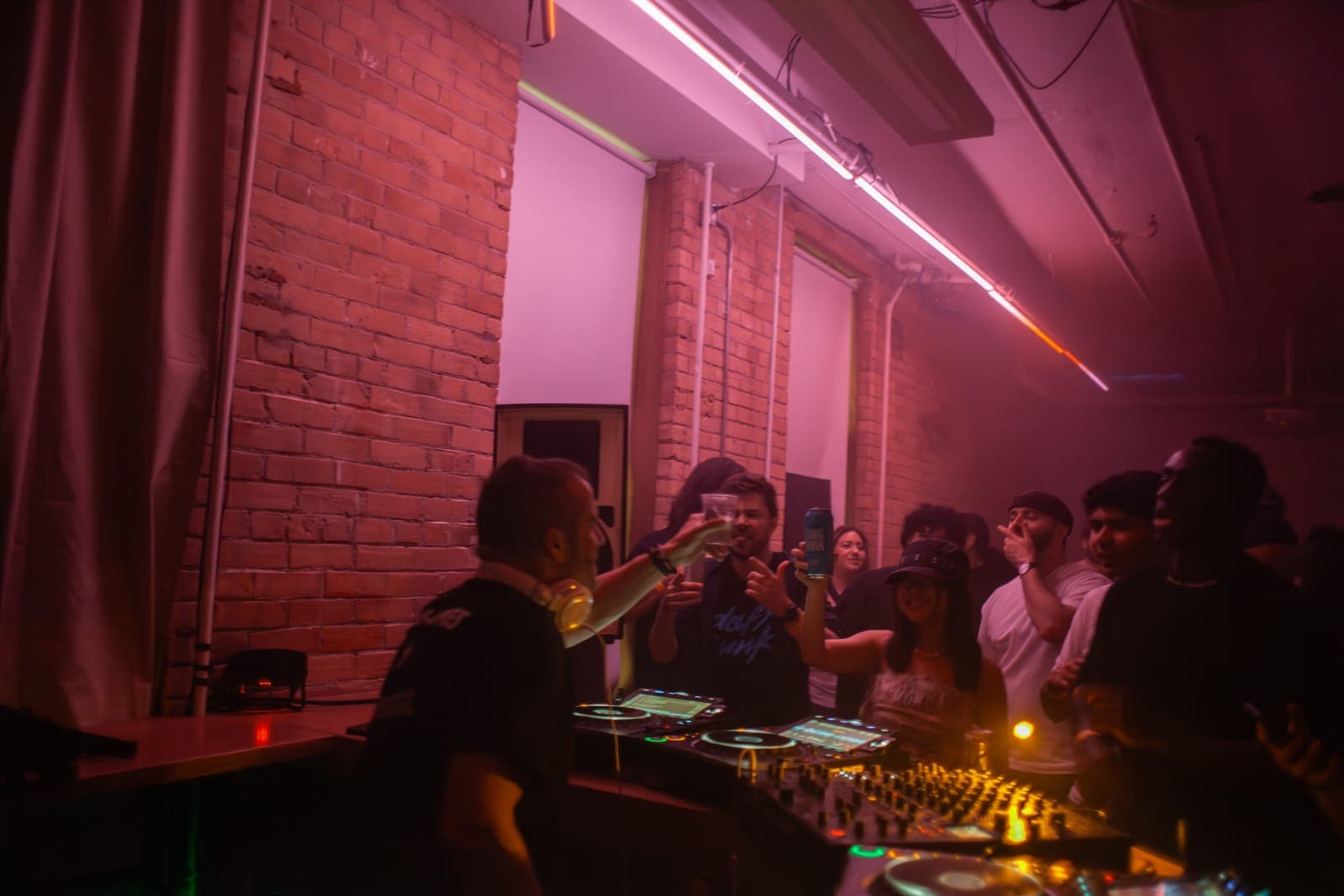 Todd Edwards toasts with the crowd over the DJ booth under purple light at Rhythm in Toronto