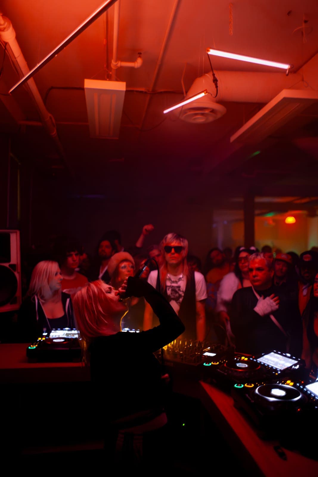 Uffie sings into the mic facing the crowd under warm red light at Rhythm in Toronto